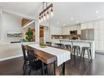 Open-concept dining room adjacent to kitchen, featuring dark wood floors and a modern light fixture at 2067 E Phillips Pl, Centennial, CO 80122