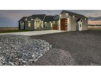 Stunning home exterior with modern garage doors, professional landscaping, and beautiful architectural lighting at 29780 E 162Nd Ave, Brighton, CO 80603