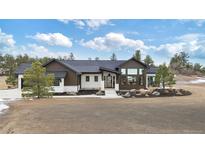 Luxury ranch home with a welcoming front porch and expansive windows at 1571 Arrowpoint Ct, Franktown, CO 80116