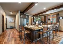 Spacious kitchen features an island with seating and granite countertops, wood floors, and beamed ceiling at 8090 S Homesteader Dr, Morrison, CO 80465