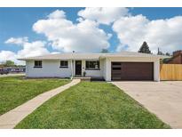 Charming, freshly painted home with a well-manicured lawn and modern garage door at 6068 Lee St, Arvada, CO 80004