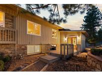 Tan home exterior with a wooden deck and well-lit windows at dusk at 7841 Deertrail Dr, Parker, CO 80138