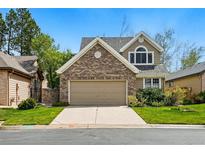Charming two-story home features a brick facade and a two-car garage with a well-manicured lawn at 2252 S Yosemite Cir, Denver, CO 80231
