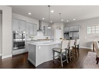 Modern kitchen with stainless steel appliances, large island with seating, and dark hardwood floors at 23252 E Glidden Dr, Aurora, CO 80016