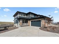 Beautiful two-story home featuring a stone facade, large driveway, and inviting front porch at 17213 W 93Rd Pl, Arvada, CO 80007