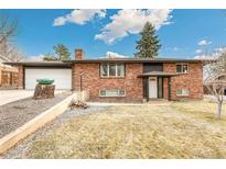 Charming brick home featuring an attached garage and mature landscaping at 6614 Everett St, Arvada, CO 80004