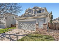 Two-story home with gray siding, brick accents, and a two-car garage, set against a clear blue sky at 20521 E Bellewood Pl, Aurora, CO 80015