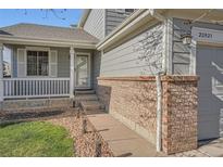 Charming home exterior with inviting front porch, brick accents and well maintained lawn and landscaping at 20521 E Bellewood Pl, Aurora, CO 80015