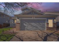 Charming home featuring a two-car garage with brick accents, set against a twilight sky at 20521 E Bellewood Pl, Aurora, CO 80015