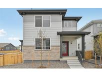 Two-story home with light gray siding, stone accents, a red door and a covered front porch at 6225 N Nepal Ct, Aurora, CO 80019
