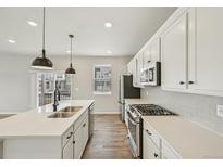 Modern kitchen featuring white cabinets, stainless steel appliances, and quartz countertops at 6225 N Nepal Ct, Aurora, CO 80019