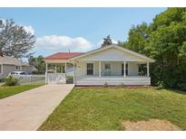 Charming single-story home with a welcoming front porch, lawn, and driveway on a sunny day at 4465 S Bannock St, Englewood, CO 80110