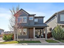 Two story house showcasing a well manicured front yard and charming porch at 6805 Canosa St, Denver, CO 80221