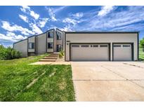 Charming exterior of two-story home featuring a spacious three-car garage and landscaped front yard at 9163 N Palomino Dr, Castle Rock, CO 80108