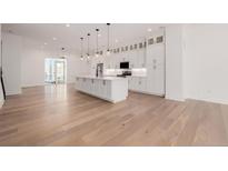 Bright, modern kitchen with large island, pendant lighting, and white cabinetry at 2361 Junegrass Ln, Louisville, CO 80027