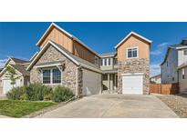 Two-story home featuring stone and wood-style siding, a well-kept lawn, and a two-car garage at 17040 Galapago Ct, Broomfield, CO 80023