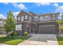 Charming two-story home featuring a stone facade, two-car garage, and manicured front yard under a bright sky at 1195 Fox Hills Ct, Erie, CO 80516