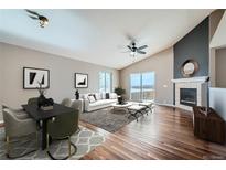 Bright living room featuring vaulted ceiling, fireplace, hardwood floors, and a modern dining table at 4296 Clover Ln, Brighton, CO 80601