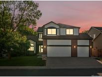 Two-story home featuring a three-car garage, white siding, and beautiful landscaping at sunset at 12695 Wolff St, Broomfield, CO 80020