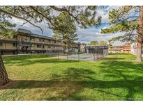 Community pool with lawn area and multifamily building in the background at 1723 Robb St # 44, Lakewood, CO 80215