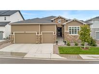 Charming home with a three-car garage, stone accents, landscaped yard, and inviting front entrance at 228 Rogers Ct, Castle Rock, CO 80104