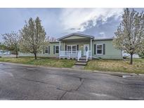 Charming single-story home features a welcoming front porch and well-maintained lawn with flowering trees at 7971 Larkspur Cir # 219, Frederick, CO 80530