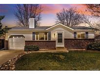 Charming single-story home featuring a brick facade, lush lawn, and inviting landscaping at 9825 W Walker Pl, Littleton, CO 80123