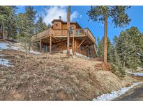 Hillside home with a spacious deck, wood siding, and stairway at 7219 S Brook Forest Rd, Evergreen, CO 80439