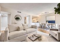 Bright living room boasts a comfortable sofa, stylish decor, and an open layout to the dining area at 14006 E Stanford Cir # K04, Aurora, CO 80015