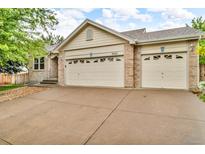 A home's exterior is defined by its brick accents and a two-car garage, with a concrete driveway at 5960 S Estes St, Littleton, CO 80123
