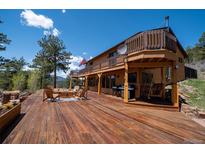 Expansive wooden deck with outdoor seating, grill, and scenic views of the surrounding landscape at 351 N Saddle Dr, Idaho Springs, CO 80452