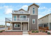 Two-story home with gray siding, multiple balconies, and landscaped yard at 45060 Sunflower Ln, Bennett, CO 80102