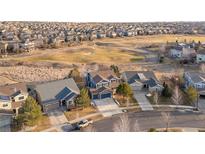 Expansive aerial view of homes bordering the golf course in a peaceful neighborhood, featuring lush greenery and well-maintained lawns at 1870 Alpine Dr, Erie, CO 80516