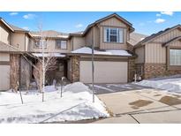 Two-story townhome with attached garage and snow-covered landscaping at 7662 Bristolwood Dr, Castle Pines, CO 80108