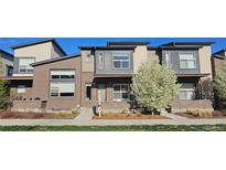 Contemporary townhome featuring a brick facade, modern windows, and beautifully landscaped front yard at 10066 Belvedere Cir, Lone Tree, CO 80124