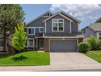 Charming two-story home features a well-manicured lawn, gray siding and a spacious two car garage at 17018 Carr Ave, Parker, CO 80134