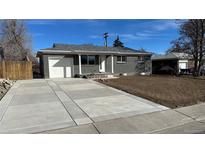 Charming single-story brick home featuring an attached garage and a long, newly refinished concrete driveway at 121 Joan Dr, Denver, CO 80221