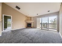 Open living room featuring a fireplace and sliding glass doors leading to a balcony at 7415 S Alkire St # 302, Littleton, CO 80127