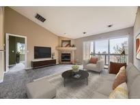 Comfortable living room with fireplace, large windows, and balcony access at 7415 S Alkire St # 302, Littleton, CO 80127