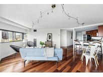Bright living room featuring hardwood floors, modern lighting, and comfortable seating arrangement at 100 Park Ave # 907, Denver, CO 80205