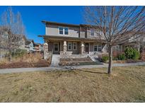 Charming two-story home with covered porch, stone accents, and landscaped front yard on a sunny day at 2936 Iola St, Denver, CO 80238