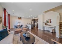 Open-concept living room features hardwood floors, modern lighting, and a stylish dining area and kitchen at 2936 Iola St, Denver, CO 80238