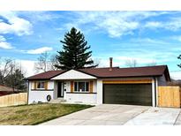 Charming single-story home with a well-manicured lawn, mature trees, and a two-car garage at 1853 S Urban Way, Lakewood, CO 80228
