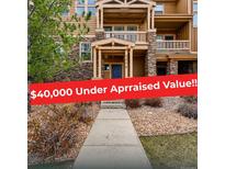 Inviting townhouse featuring a stone facade, covered balconies, and well-maintained landscaping at 5574 W 72Nd Dr, Arvada, CO 80003