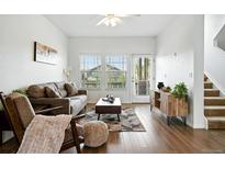 Bright living room features hardwood floors, neutral paint, large windows, and stylish furnishings at 5574 W 72Nd Dr, Arvada, CO 80003