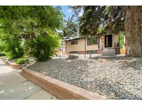 Charming single-Gathering home with brick accents, landscaped with decorative rock, mature trees, and concrete walkway at 1243 Monroe St, Denver, CO 80206
