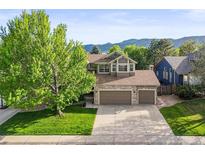 Charming home with a stone facade, two-car garage, and large tree in the front yard at 9162 W Unser Ave, Littleton, CO 80128