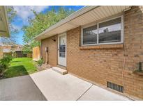 Brick exterior of home with access door, window, and concrete patio at 7902 Meade St # A10, Westminster, CO 80030