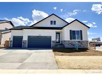 Charming two-story home with a three car garage, stone accents, and black trim against white siding at 25204 E Warren Pl, Aurora, CO 80018