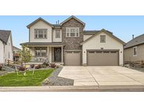 Charming two-story home features a stone facade and a spacious three-car garage with a landscaped front yard at 1403 Hart Ln, Elizabeth, CO 80107